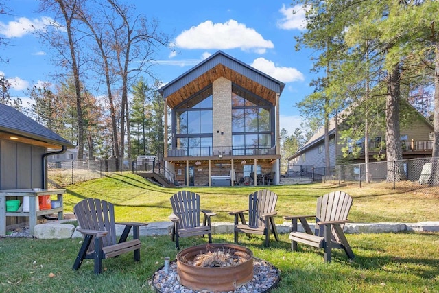 back of property with a yard and a fire pit