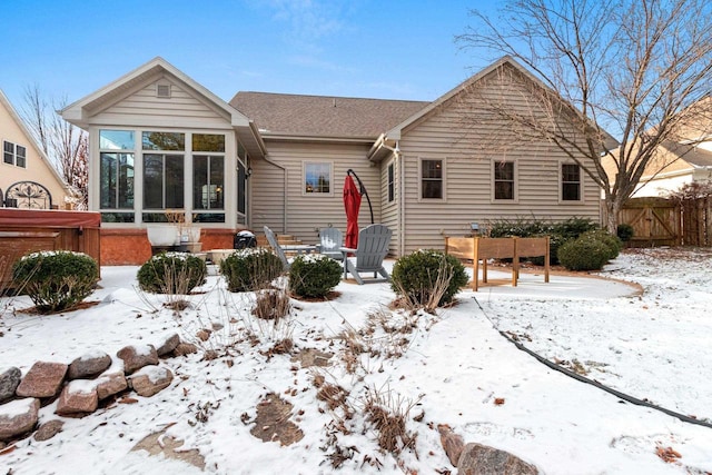 snow covered property with a sunroom and a hot tub