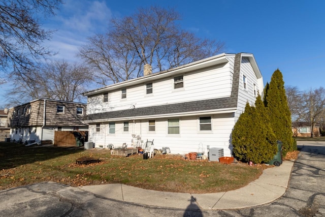 back of property featuring a yard and central AC