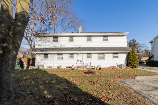 rear view of property with a lawn and central air condition unit