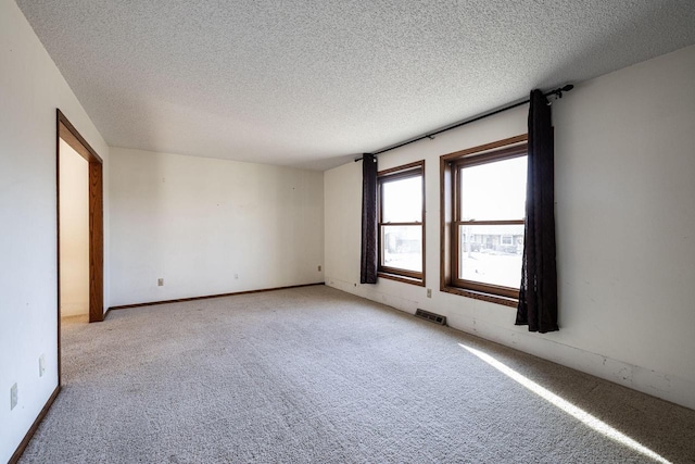 carpeted empty room featuring a textured ceiling