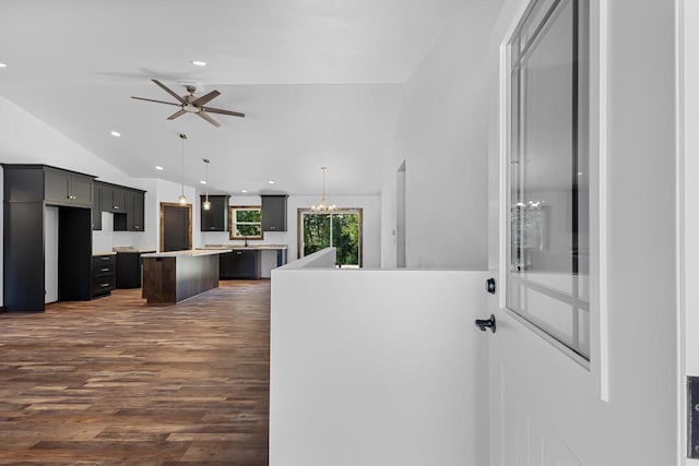 kitchen with hanging light fixtures, dark hardwood / wood-style flooring, vaulted ceiling, a kitchen island, and ceiling fan with notable chandelier