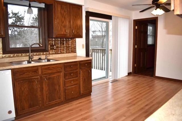 kitchen with dishwasher, backsplash, sink, light hardwood / wood-style flooring, and ceiling fan