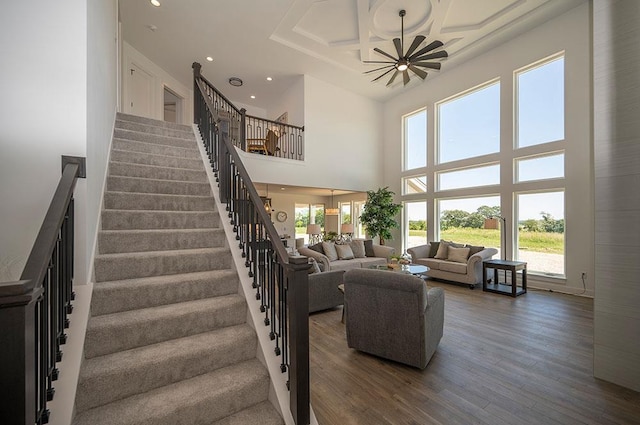 stairway with hardwood / wood-style floors, a towering ceiling, and a notable chandelier