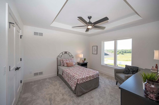 carpeted bedroom featuring a tray ceiling and ceiling fan