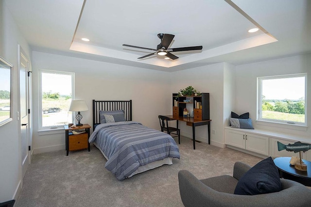 carpeted bedroom with a raised ceiling and ceiling fan