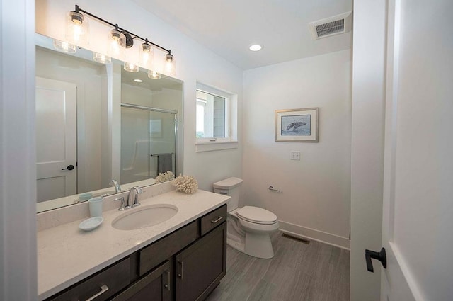 bathroom featuring hardwood / wood-style floors, vanity, toilet, and a shower with shower door