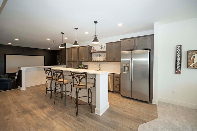 kitchen featuring sink, decorative light fixtures, a kitchen bar, dark brown cabinets, and appliances with stainless steel finishes