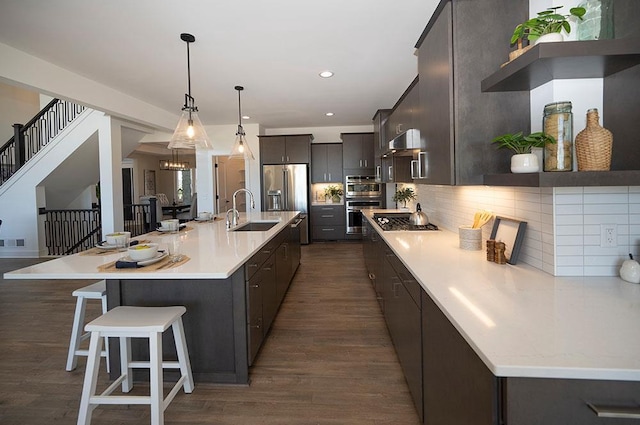 kitchen featuring sink, a kitchen breakfast bar, dark hardwood / wood-style flooring, a large island with sink, and decorative light fixtures