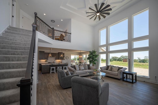 living room with ceiling fan, dark hardwood / wood-style flooring, and a towering ceiling