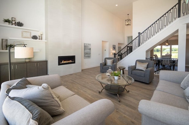 living room featuring a fireplace, hardwood / wood-style floors, an inviting chandelier, and a high ceiling