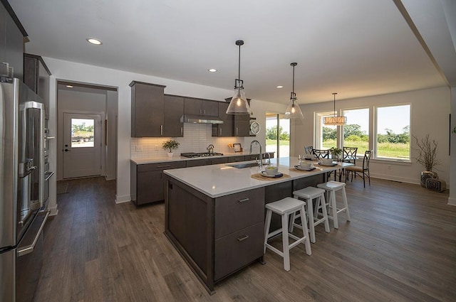 kitchen featuring a kitchen island with sink, sink, decorative backsplash, dark hardwood / wood-style floors, and appliances with stainless steel finishes