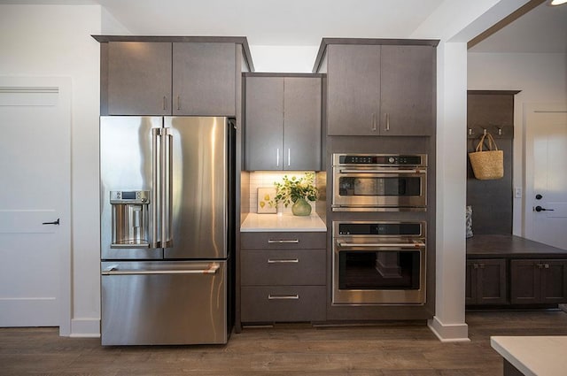 kitchen featuring backsplash, dark wood-type flooring, and appliances with stainless steel finishes