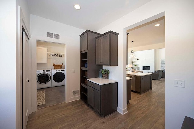 kitchen with independent washer and dryer, dark brown cabinets, and dark wood-type flooring