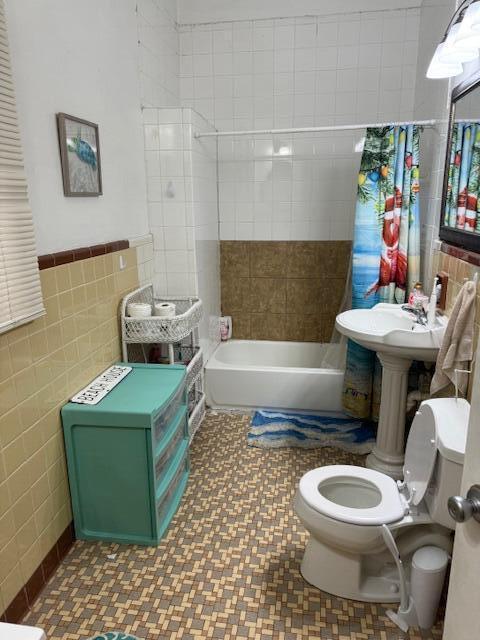 bathroom featuring shower / bath combo, toilet, and tile walls