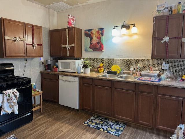 kitchen with decorative backsplash, white appliances, dark wood-type flooring, and sink