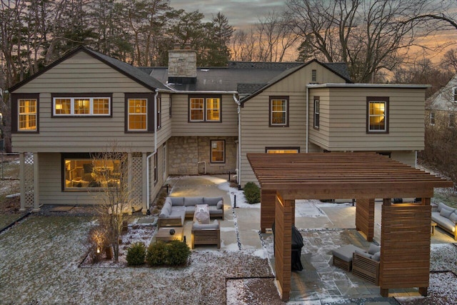 back house at dusk with an outdoor living space with a fireplace, a pergola, and a patio