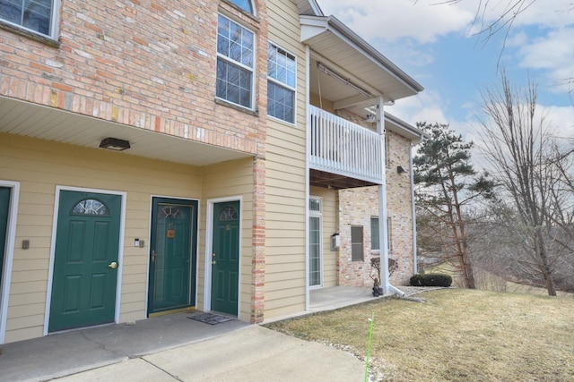 doorway to property featuring a lawn and a balcony