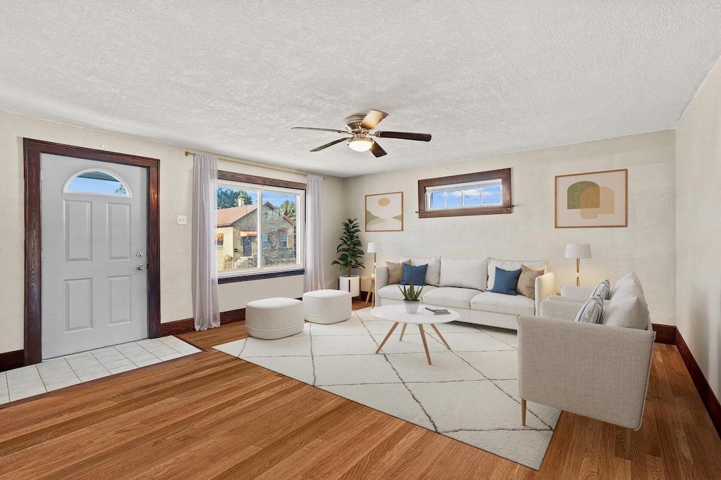 living room featuring ceiling fan, wood-type flooring, and a textured ceiling