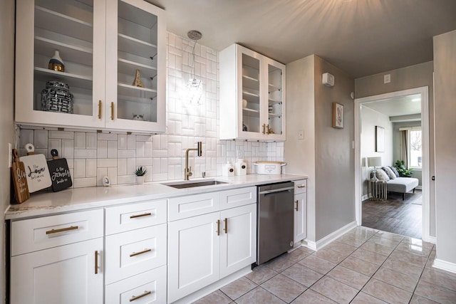 kitchen with sink, light tile patterned floors, stainless steel dishwasher, decorative backsplash, and white cabinets