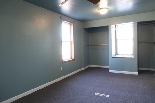 unfurnished bedroom with dark carpet and a closet