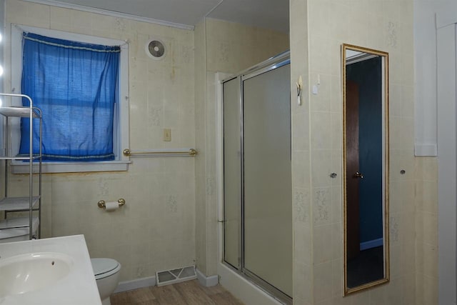 bathroom with vanity, hardwood / wood-style flooring, toilet, tile walls, and walk in shower