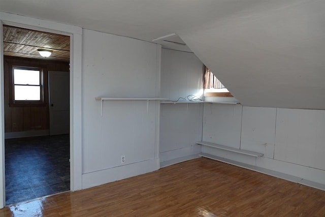 bonus room with vaulted ceiling, wood walls, and dark hardwood / wood-style floors