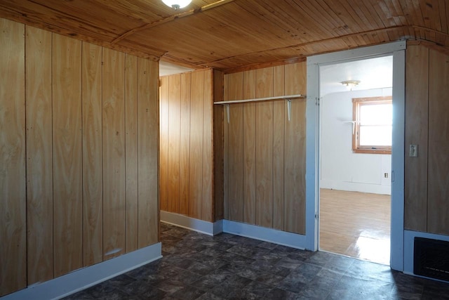 unfurnished room with wooden ceiling and wooden walls