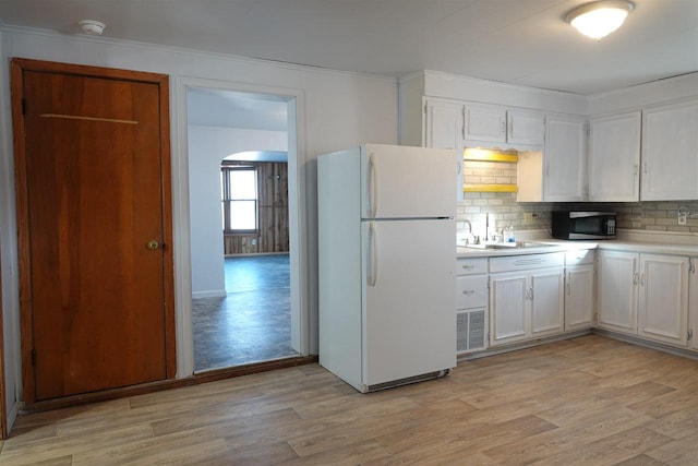 kitchen featuring decorative backsplash, light wood-type flooring, sink, white refrigerator, and white cabinetry