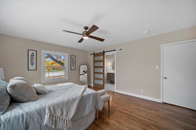 bedroom featuring a barn door, ceiling fan, and hardwood / wood-style flooring