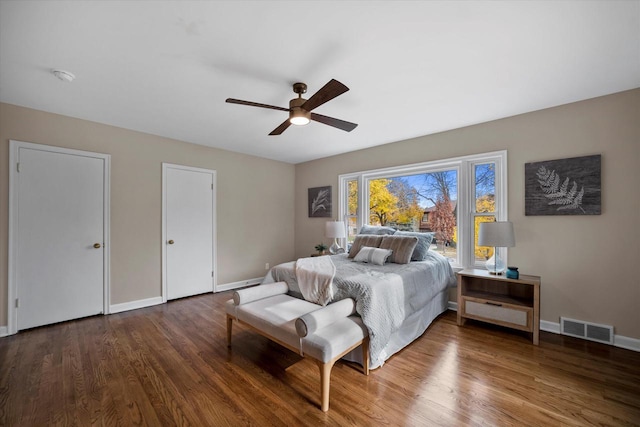 bedroom featuring multiple closets, ceiling fan, and wood-type flooring