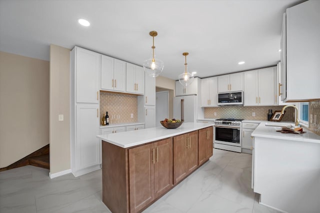 kitchen featuring decorative backsplash, sink, white refrigerator, a center island, and stainless steel stove