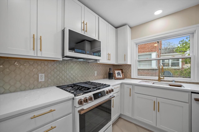 kitchen with high end range, white cabinets, sink, decorative backsplash, and light stone countertops