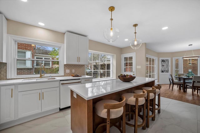 kitchen featuring tasteful backsplash, dishwasher, decorative light fixtures, and sink