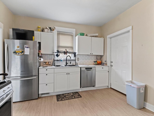 kitchen with stainless steel appliances, white cabinetry, and tasteful backsplash