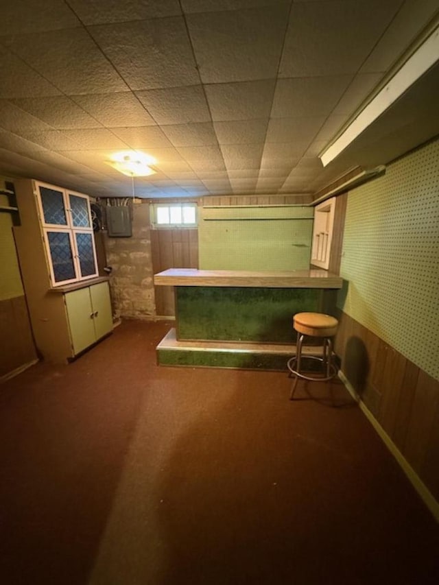 basement with bar area, electric panel, and wood walls