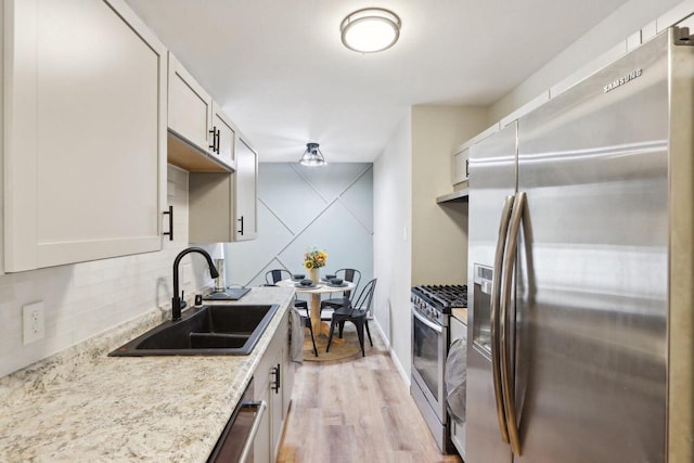 kitchen with decorative backsplash, appliances with stainless steel finishes, light hardwood / wood-style flooring, and sink