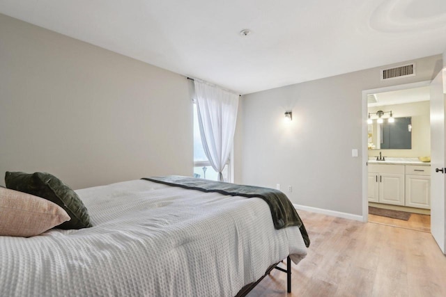 bedroom featuring light wood-type flooring, sink, and ensuite bath