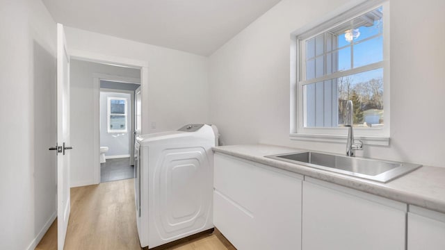 laundry room with cabinets, washer / dryer, light hardwood / wood-style floors, and sink