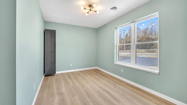 spare room featuring light hardwood / wood-style floors and an inviting chandelier