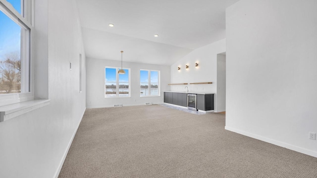 unfurnished living room with carpet floors, beverage cooler, and vaulted ceiling