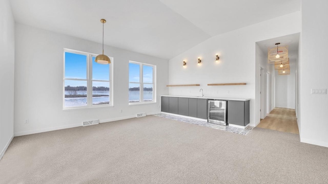 unfurnished living room featuring lofted ceiling, a water view, sink, light colored carpet, and beverage cooler