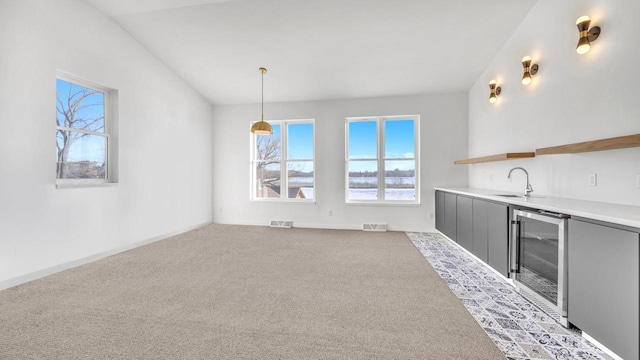 interior space featuring carpet flooring, sink, wine cooler, lofted ceiling, and decorative light fixtures