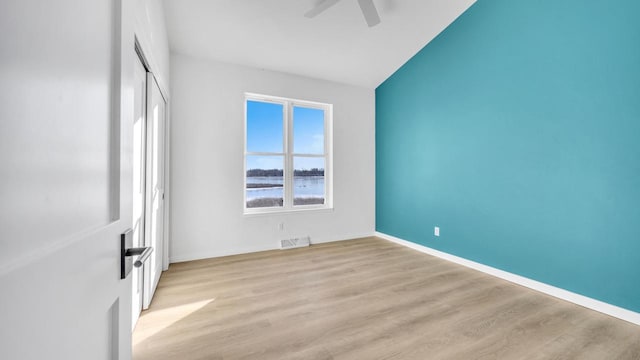 spare room with a water view, light hardwood / wood-style flooring, and ceiling fan