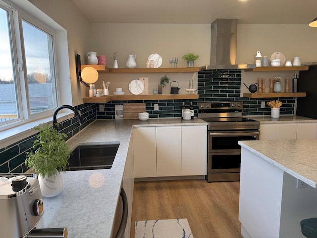 kitchen featuring sink, wall chimney exhaust hood, stainless steel appliances, light hardwood / wood-style flooring, and white cabinets