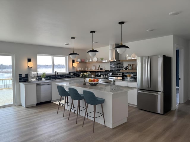 kitchen featuring a center island, white cabinets, appliances with stainless steel finishes, light hardwood / wood-style floors, and island exhaust hood