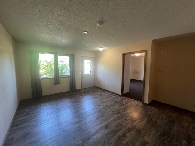 unfurnished room with plenty of natural light, dark wood-type flooring, and a textured ceiling