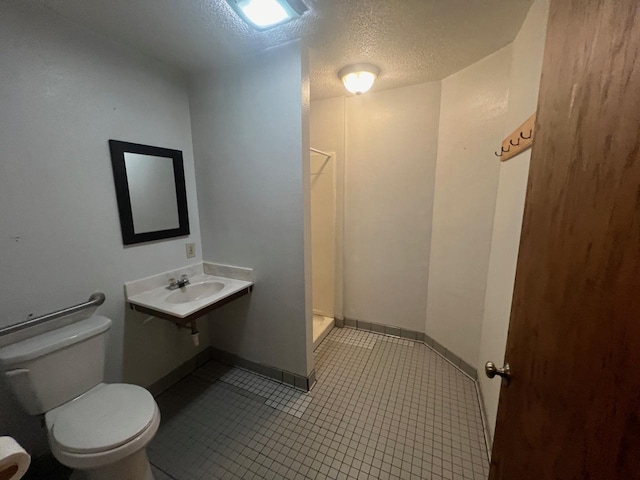 bathroom featuring a textured ceiling, sink, a shower, tile patterned flooring, and toilet