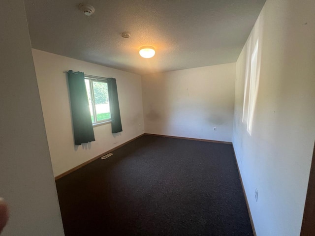 carpeted empty room with a textured ceiling