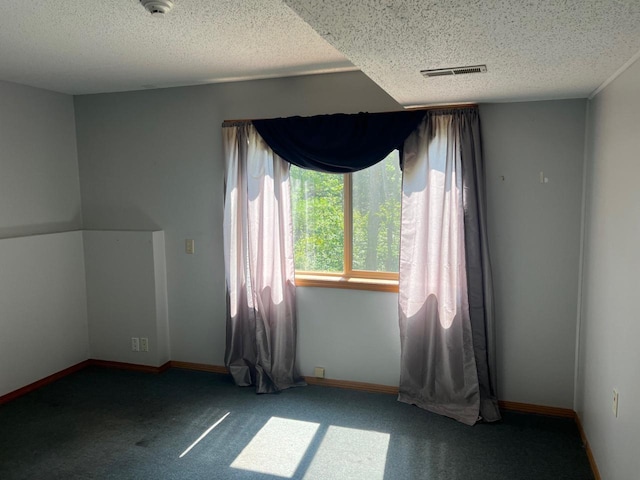 carpeted empty room featuring a textured ceiling